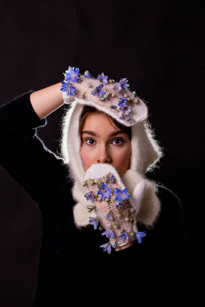 girl in mittens decorated with flowers with a surprised expression - Valokuva, kuva