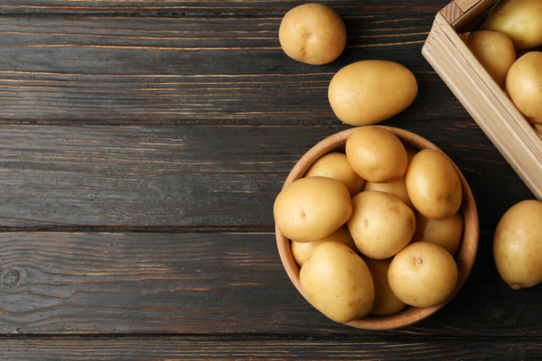 Bowl and basket with young potato on wooden background, top view - Fotografie, Obrázek