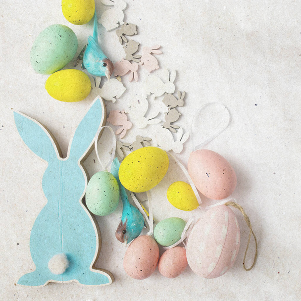 Blue wooden flat easter bunny with plastic eggs lies on a white background. Copy space. textured stylish old paper background, square, - Zdjęcie, obraz