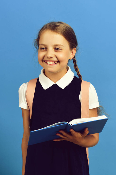 Girl holds big blue book or notebook. Happy school girl - Φωτογραφία, εικόνα