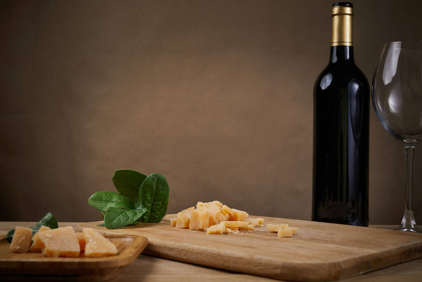 Hard cheese, greens and glass of red wine. On a dark, gray background. Copy space - Фото, изображение