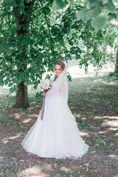 Amazing bride in beautiful white wedding dress hold bouquet of flowers in her hands. - Foto, Imagen