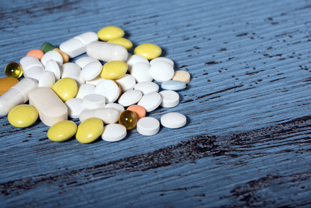 Verschillende gekleurde medicijnen en tabletten op blauwe textuur achtergrond. Concept van de gezondheidszorg. Kopieerruimte. - Foto, afbeelding