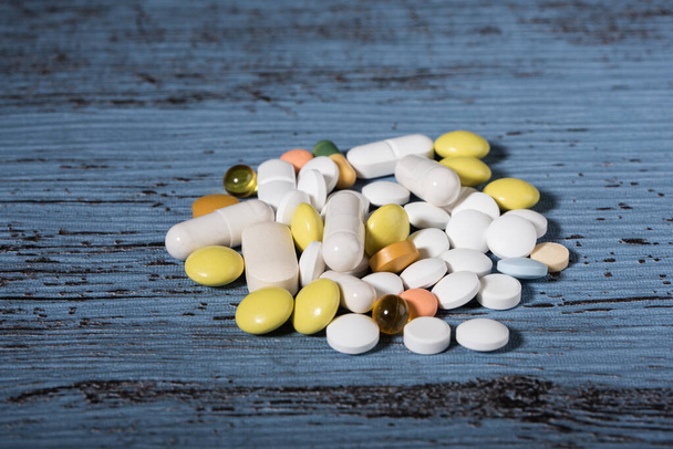 Verschiedene farbige Medikamente und Tabletten auf blauem Hintergrund. Konzept des Gesundheitswesens. Kopierraum. - Foto, Bild