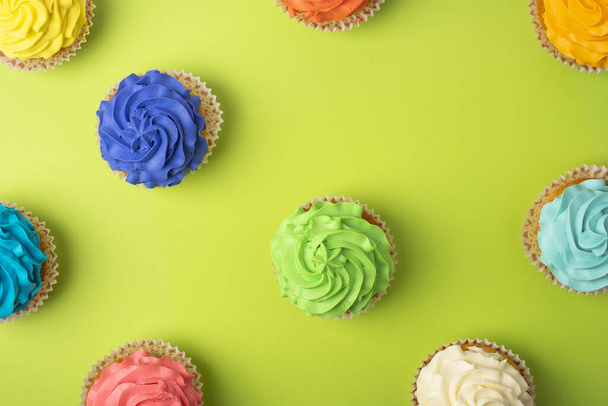 Party background with different cupcakes on bright green background. Pattern with cupcakes with colorful icing. - Photo, Image