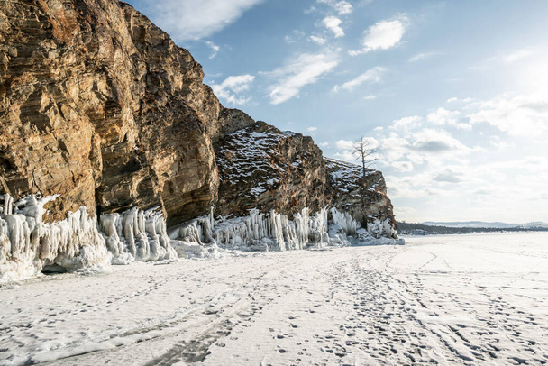 Skała na lodzie zimowego Baikal na wyspie Olkhon na Syberii. Piękna przyroda: góry, zamarznięte jezioro, błękitne niebo. - Zdjęcie, obraz