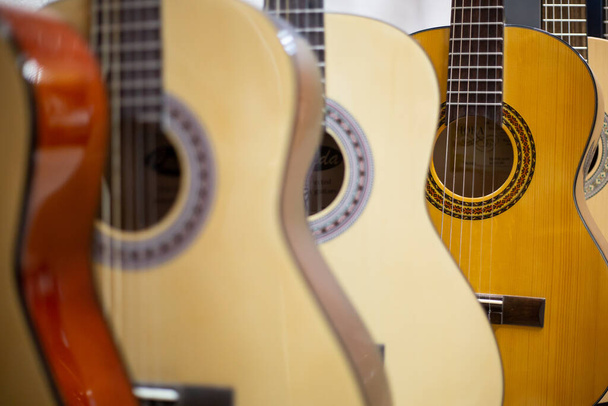 Close up de guitarra clássica drapeado em uma fileira em uma enorme loja musical, loja de instrumentos, conceito de instrumento
 - Foto, Imagem