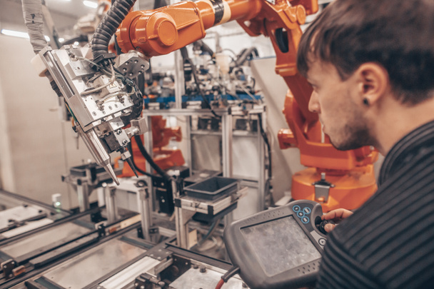 Μηχανικός, τεχνικός που εργάζεται με αυτόματο ρομπότ στην αυτοκινητοβιομηχανία, έξυπνο εργοστάσιο, αυτοματοποιημένος χώρος εργασίας - Φωτογραφία, εικόνα