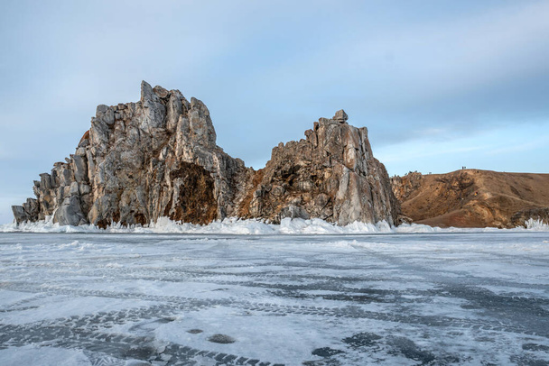 Rock on the ice of winter Baikal on Olkhon island in Siberia. Beautiful nature: mountains, frozen lake, blue sky. - Fotó, kép