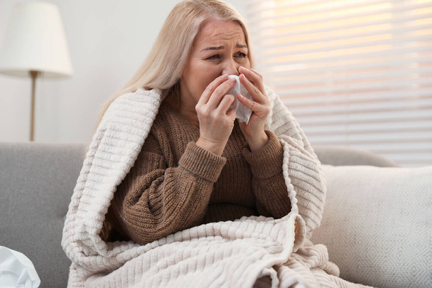 Mature woman suffering from cold at home. Dangerous virus - 写真・画像