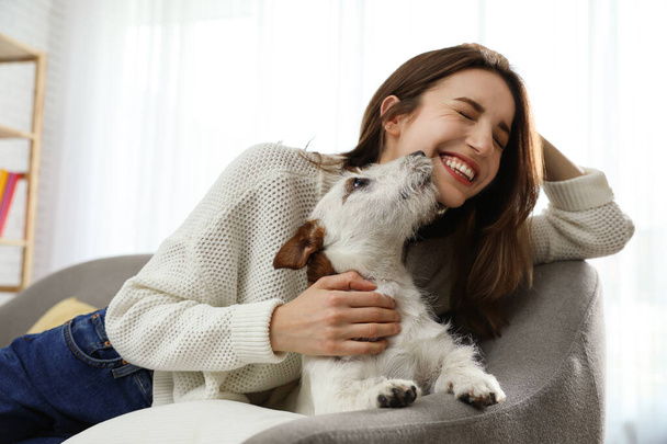 Young woman with her cute Jack Russell Terrier on sofa at home. Lovely pet - Zdjęcie, obraz