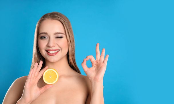 青い背景にカットレモンと若い女性。ビタミン豊富な食品 - 写真・画像