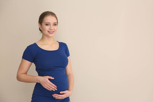 Young pregnant woman on beige background. Space for text - Zdjęcie, obraz