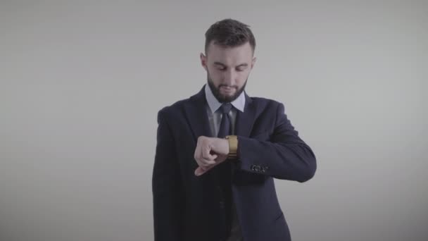 Portrait of handsome Caucasian businessman in elegant suit looking at time and tapping on watch face with finger. Serious successful young man waiting for business meeting. Entrepreneurship, lifestyle - Materiaali, video