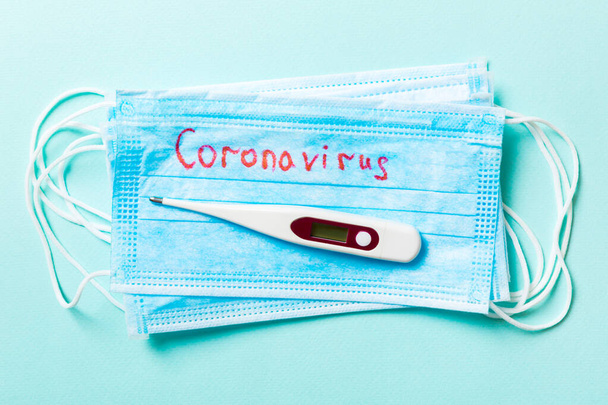 Draufsicht auf blauem Hintergrund mit Coronavirus-Wort auf medizinischen Schutzmasken und einem Thermometer. Atemwegssyndrom. Weltquarantäne-Konzept. - Foto, Bild