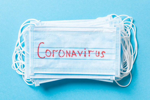Mavi arka plandaki koruyucu tıbbi maskelerin üst görüntüsü. Coronavirus kelimesi. Ncov ve covid salgını. Salgın hastalık konsepti. Sağlığınızı koruyun.. - Fotoğraf, Görsel