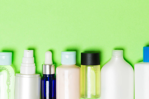Top zicht van cosmetica flessen op groene achtergrond. Skin Care concept met ruimte voor uw ontwerp. - Foto, afbeelding