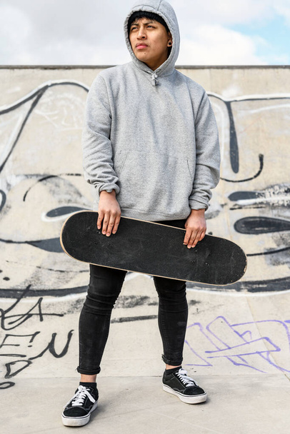 Junger Skater posiert mit Skateboard im Skatepark. - Foto, Bild