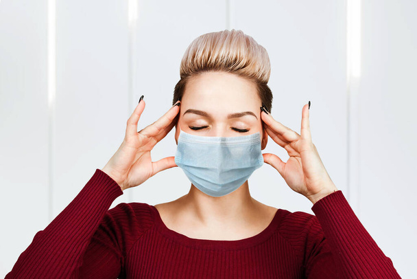 Portrait young woman has headache, wearing protective face mask prevent virus infection. - Foto, imagen