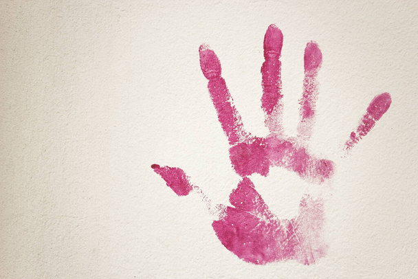 Pretty fuchsia print of hand right on white stucco surface. Artistic expression. - Photo, Image