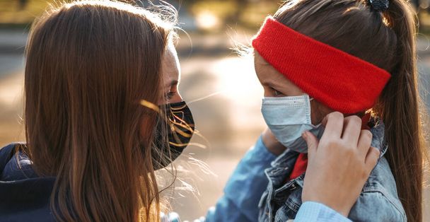 Dívka s dítětem stojí na silnici v ochranné lékařské masce. Nebezpečná virová infekce. Coronovirus v Evropě - Fotografie, Obrázek