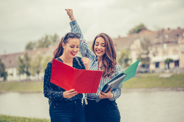 Дві жінки-друзі, студенти святкують успіх для затверджених іспитів у парку
 - Фото, зображення