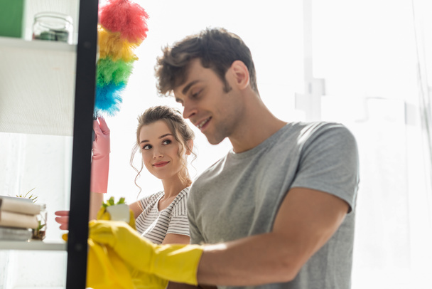 selective focus of attractive girl looking at happy man cleaning rack at home  - Photo, Image