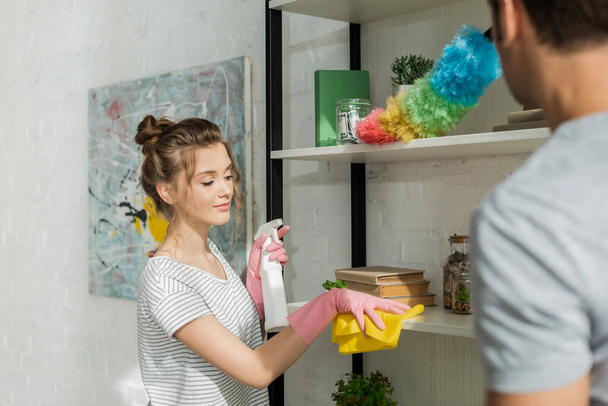 selective focus of beautiful girl cleaning shelve near man  - Photo, Image