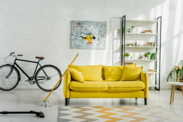 пылесос рядом с ковром и диваном в современной гостиной
  - Фото, изображение