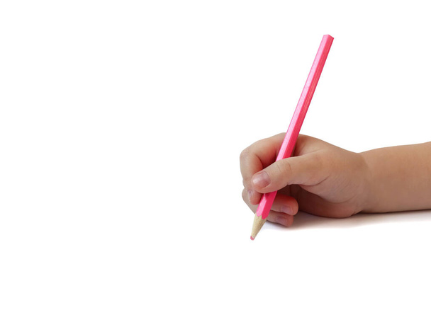 Children`s hand holds a pink pencil with the intention of drawing or writing on a white background. Copyspace. The concept of learning to write or draw. - Fotó, kép