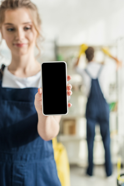 selective focus view of positive cleaner holding smartphone with blank screen - Fotografie, Obrázek
