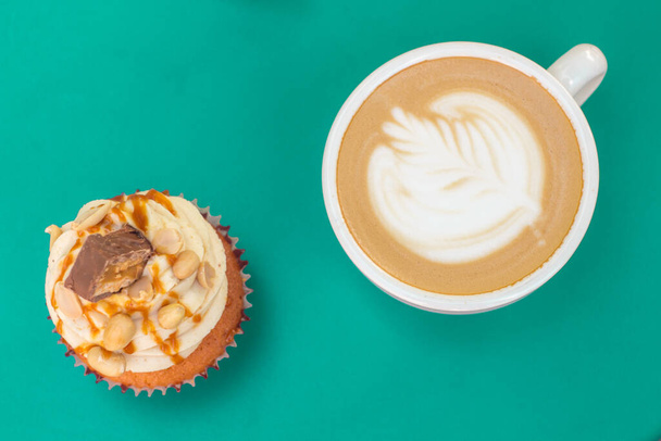 Caramel nut cupcake and cup of coffee on turquoise table - Photo, Image