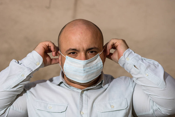 Άρρωστος νεαρός άνδρας με ιατρική προστατευτική μάσκα προσώπου απεικονίζει την πανδημία της νόσου του Coronavirus σε θολή φόντο. Εστία Covid-19 στην Ευρώπη. Έννοια μόλυνσης από γρίπη - Φωτογραφία, εικόνα