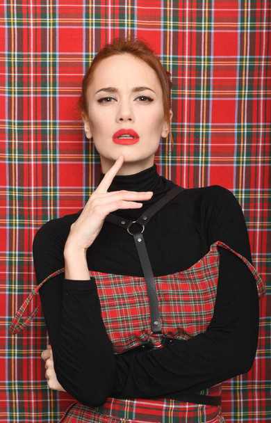 A girl in a plaid dress poses against same fabric - Photo, Image