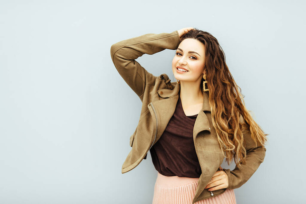 Beautiful, sexy, fashionable brown hair girl in in a brown jacket and pink skirt posing at white background - Foto, afbeelding