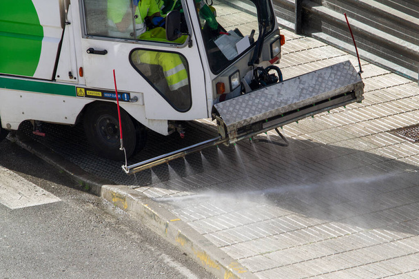 Straßenreinigungsmaschine im Einsatz in der Stadt. Kehrmaschine reinigt den Gehweg mit Druckwasser. Wartungs- oder Reinigungskonzept - Foto, Bild