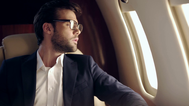 homme d'affaires sérieux regardant montre-bracelet tout en voyageant en avion
 - Séquence, vidéo