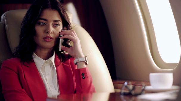 donna d'affari che parla su smartphone e controlla il tempo durante il viaggio in aereo
 - Filmati, video