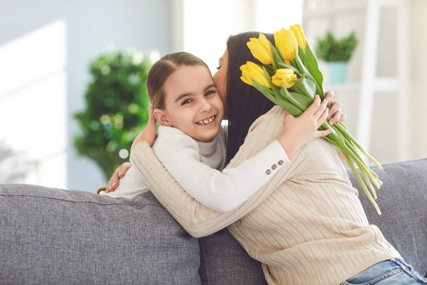 Happy mothers day. Daughter congratulates hugs his mother holds a bouquet of flowers in the room. - Photo, Image