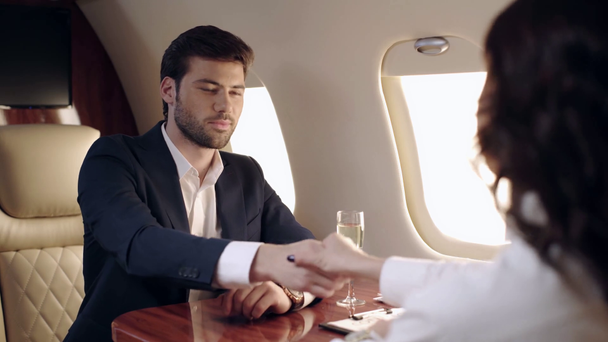 selective focus of businessman and businesswoman shaking hands in plane - Záběry, video