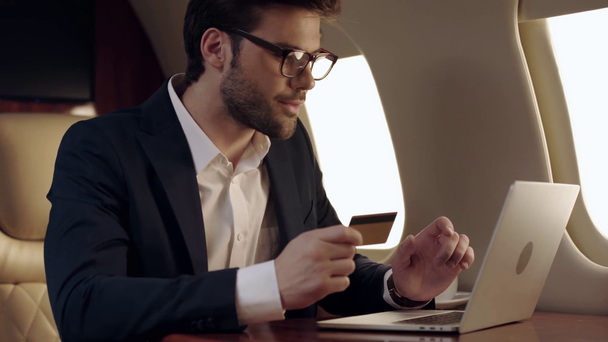 zakenman met laptop en houder van een creditcard tijdens het reizen met het vliegtuig - Video