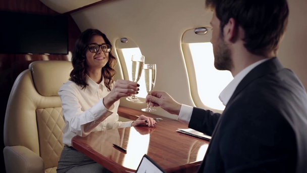 twee zakenmensen tekenen contract en klappen champagne glazen in het vliegtuig - Video