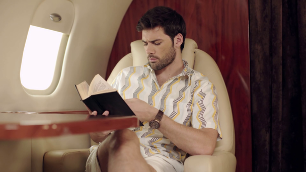 серйозна людина розмовляє і читає книгу під час подорожі літаком
 - Кадри, відео