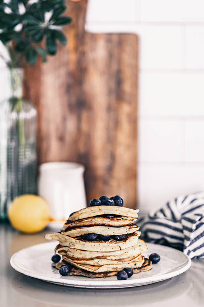 Lemon poppy seed pancakes on grey plate. Fresh blueberries on top. Maple syrup drizzle. Stack of warm pancakes. Breakfast brunch time. Kitchen countertop. Lifestyle food photography. Fluffy pancakes. - Valokuva, kuva