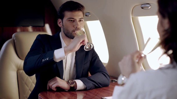 selective focus of two businesspeople clinking champagne glasses in plane - Πλάνα, βίντεο