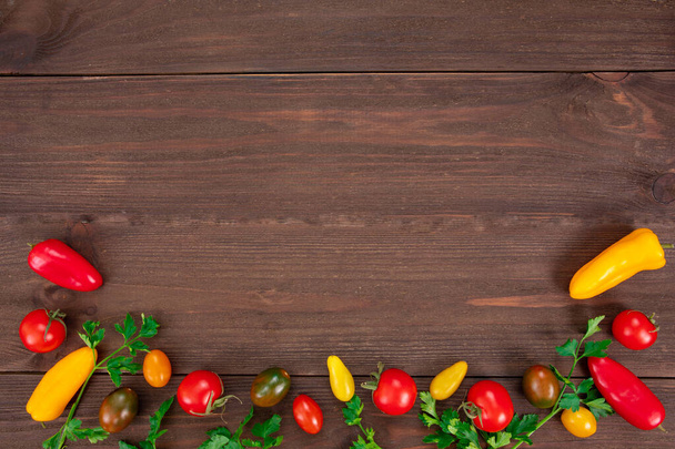 Состав с сырыми овощами, разноцветными помидорами черри, перцем и петрушкой на деревянном фоне. Биопродукты, вид сверху с копировальным пространством
 - Фото, изображение