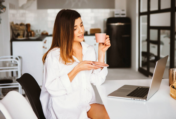 Happy beautiful woman in white shirt working on a laptop. - Φωτογραφία, εικόνα