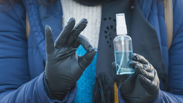 Close-up of young person holding in the hand antiseptic or anti bacteria spray. Disinfecting hands. Concept of health care during an epidemic or pandemic - 写真・画像