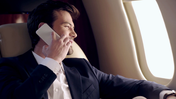 zelfverzekerde zakenman praten op smartphone tijdens het reizen met het vliegtuig - Video