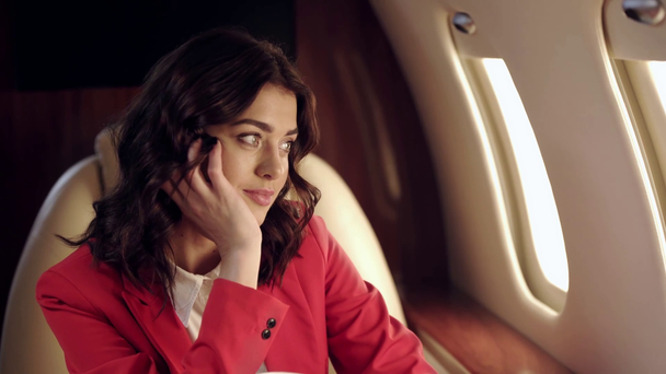 mujer de negocios soñadora mirando en iluminador mientras viaja en avión
 - Imágenes, Vídeo